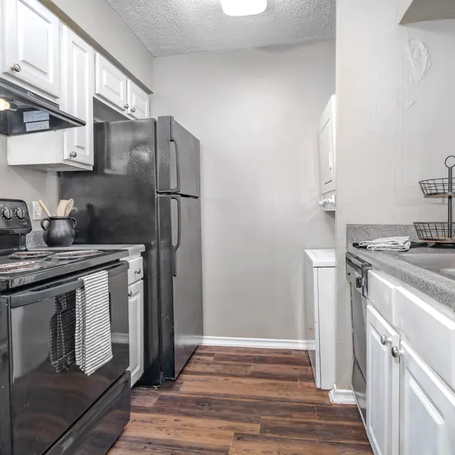 A contemporary kitchen featuring white cabinets, black appliances, and a double sink with a countertop.