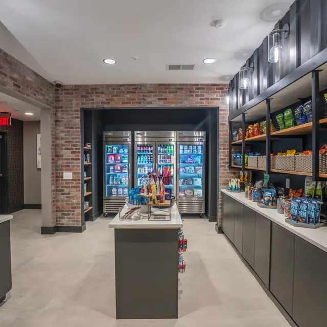 A well-organized modern convenience store with shelves stocked with snacks, drinks, and other products. The space features a cool color palette and contemporary design elements, with brick accents and well-lit shelves.