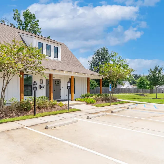 Exterior of a Building with Parking Exterior view of a building with a pitched roof, surrounded by green landscaping and parking spaces.