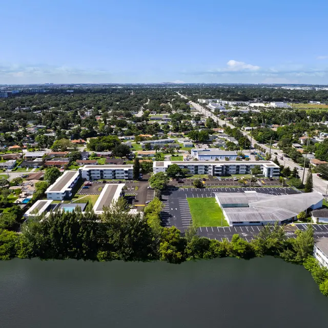 Aerial view of a suburban area featuring residential homes, a lake, and commercial buildings.