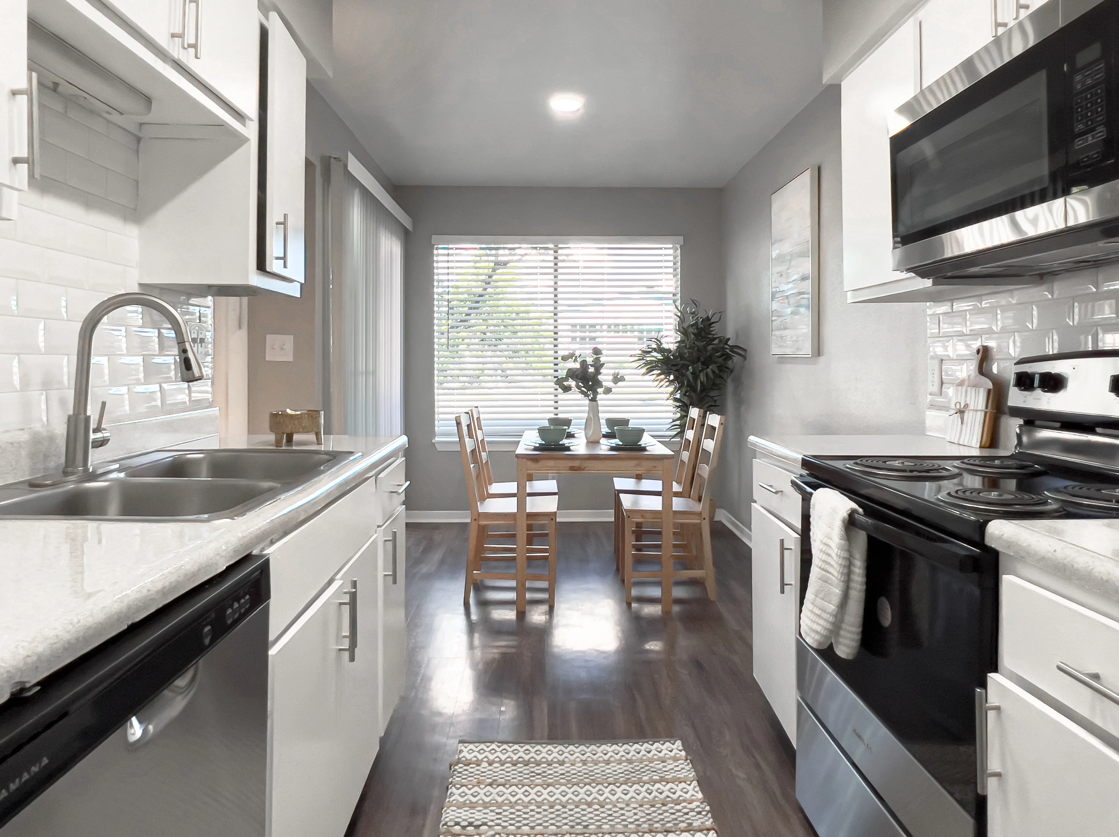 Regatta Bright and modern kitchen with a dining area, featuring white cabinets, stainless steel appliances, and a table set for four.