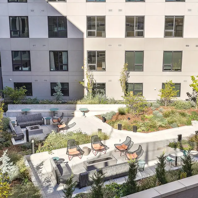 Urban Courtyard Scene A serene urban courtyard with green landscaping, seating areas, and small trees surrounded by modern buildings.