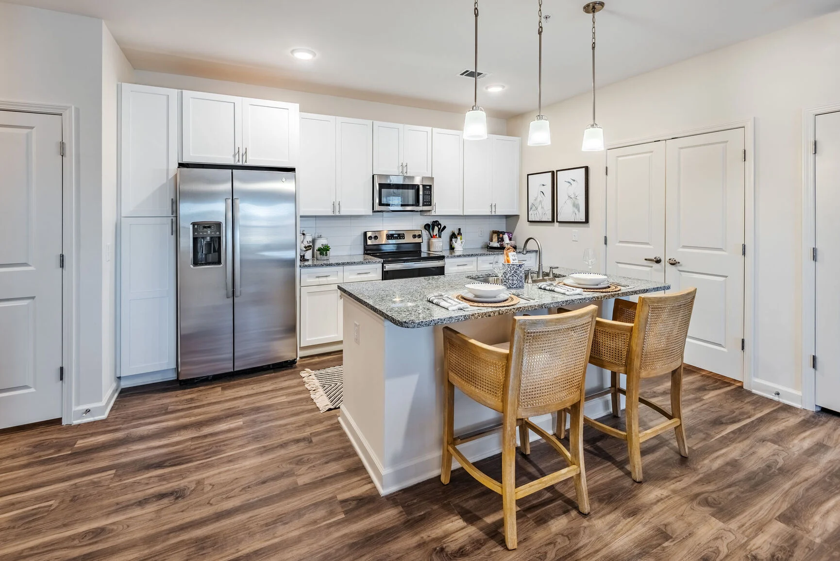 Modern Kitchen Interior A modern kitchen featuring white cabinets, stainless steel appliances, and a granite countertop with bar stools.
