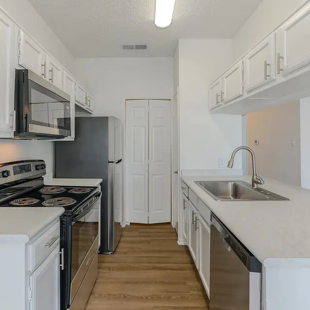 A modern kitchen featuring white cabinets, stainless steel appliances, and a sleek countertop.