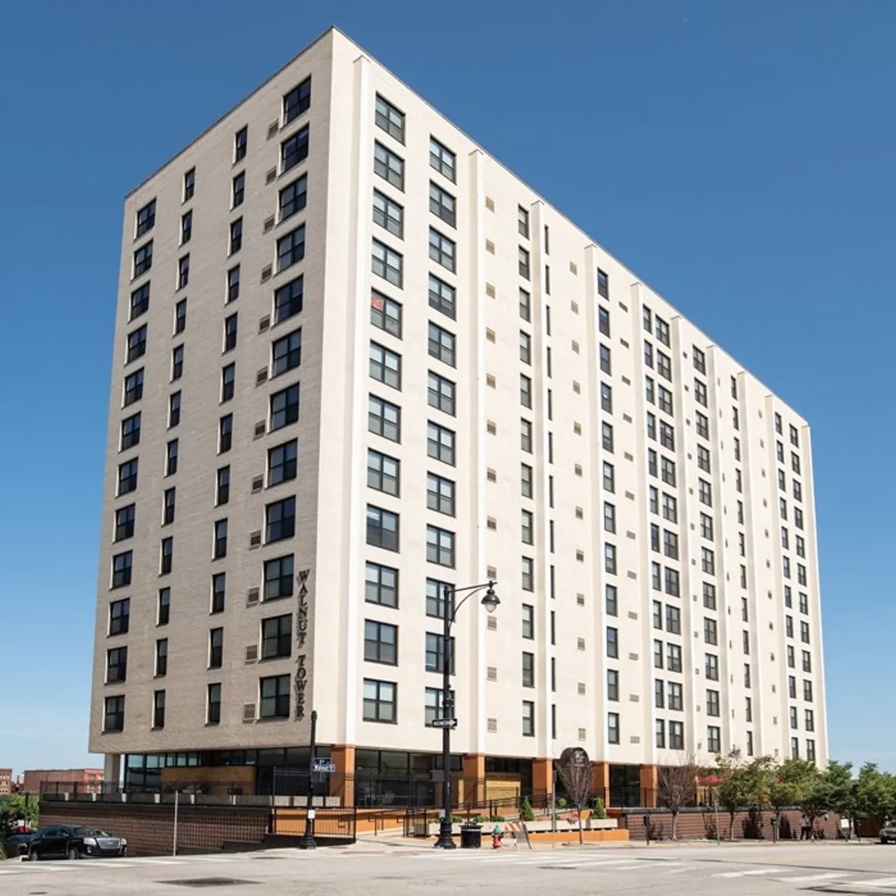 Modern High-Rise Building A tall, modern high-rise building made of light-colored brick with numerous windows, set against a clear blue sky.