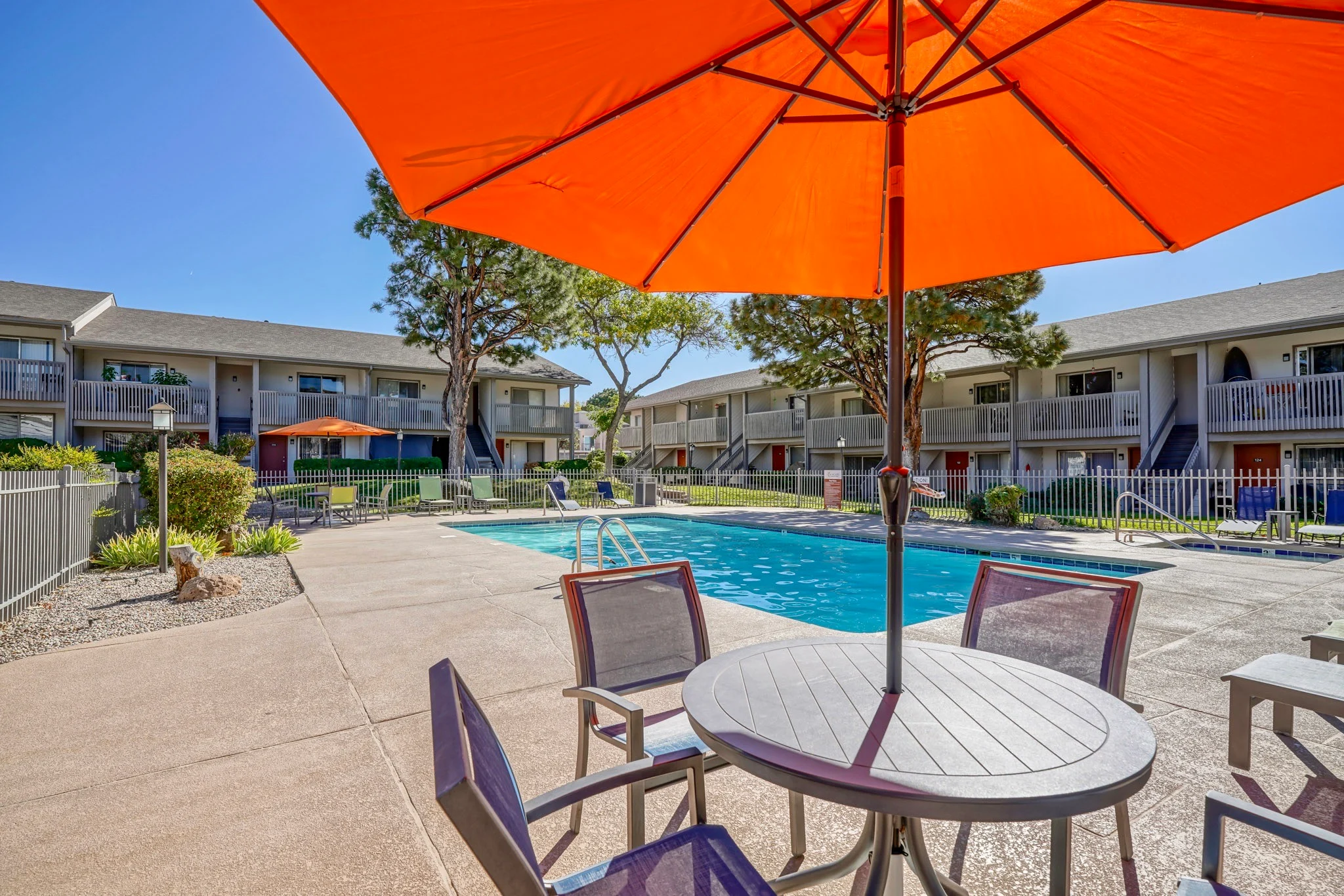 Relaxing Pool Area A sunny pool area with lounge chairs and umbrellas in an apartment complex.