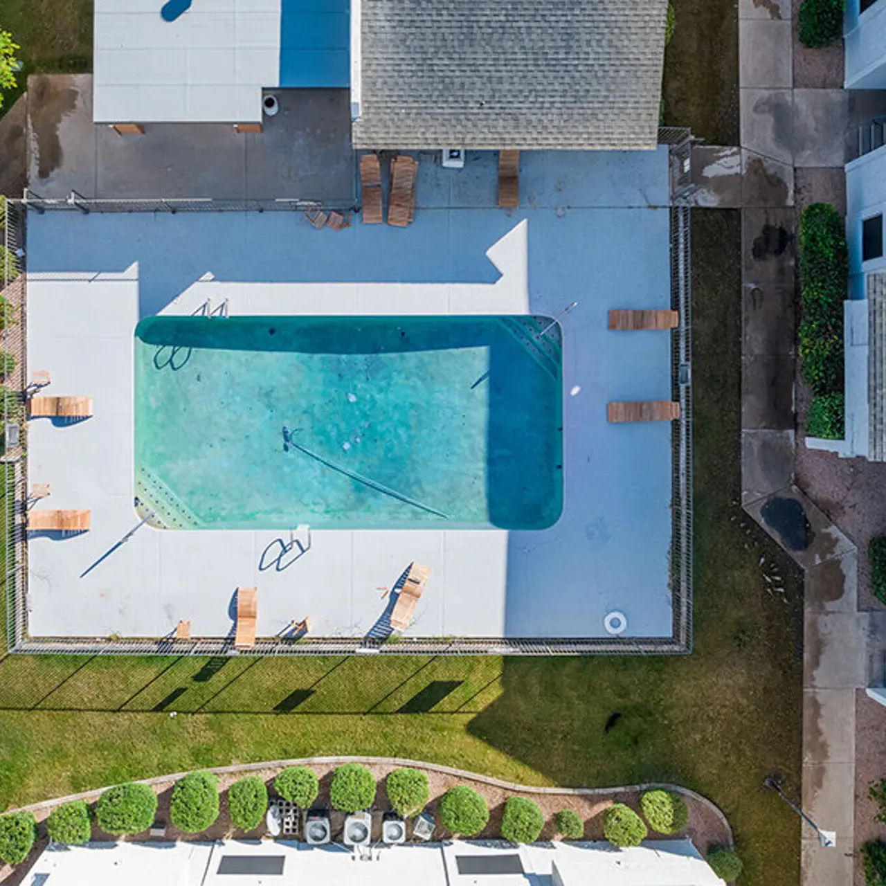 Aerial view of a spacious swimming pool surrounded by lounge chairs and greenery.