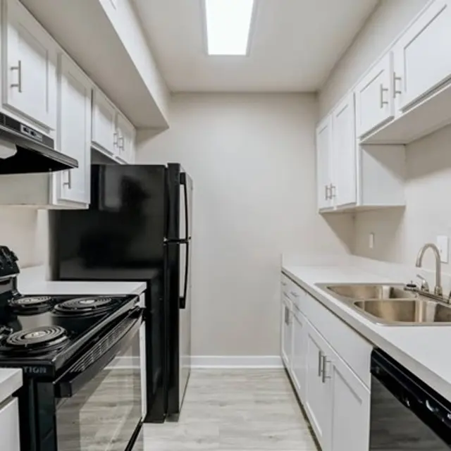 Modern kitchen with white cabinets, black appliances, and a bright ceiling light.