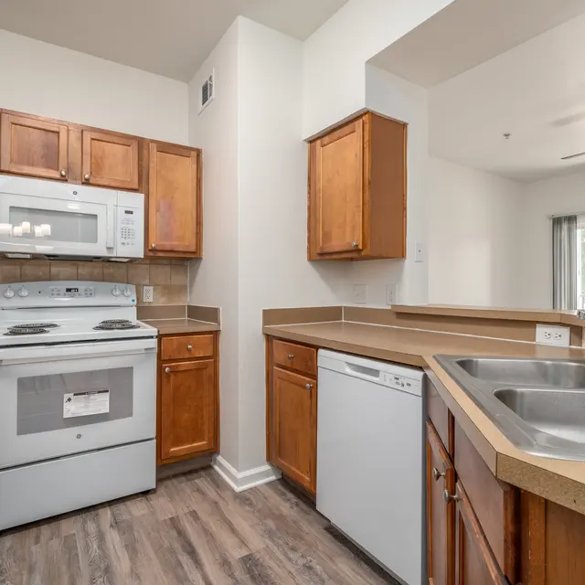Modern Kitchen Design A modern kitchen featuring wooden cabinetry, a white stove and microwave, a dishwasher, and a double sink with a view outside.