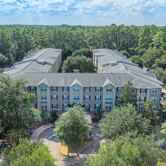 Aerial view of an apartment complex surrounded by lush greenery and trees.