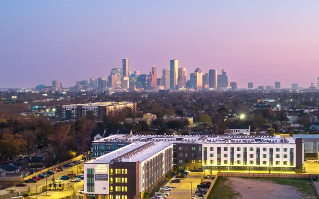 An aerial view of Houston's skyline at dusk with a mix of modern buildings and green space in the foreground.