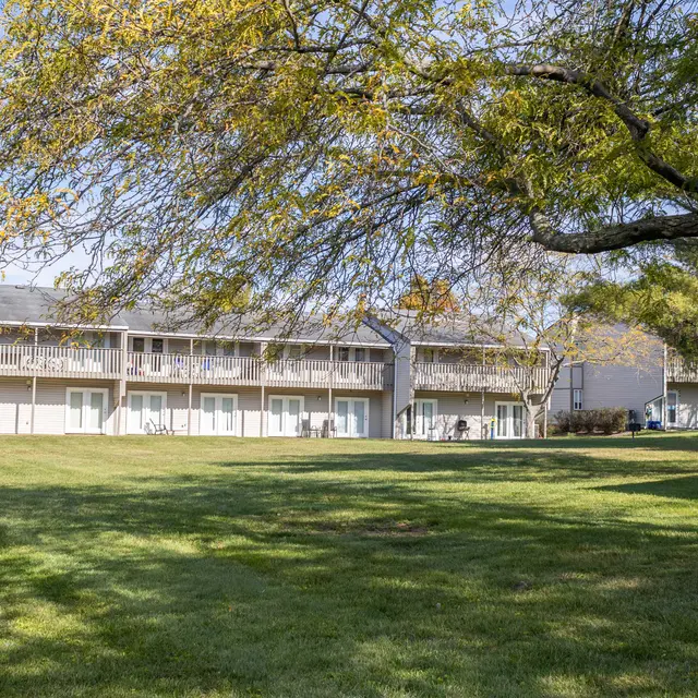 A view of a hotel or building complex surrounded by a lush green lawn and trees in the foreground.