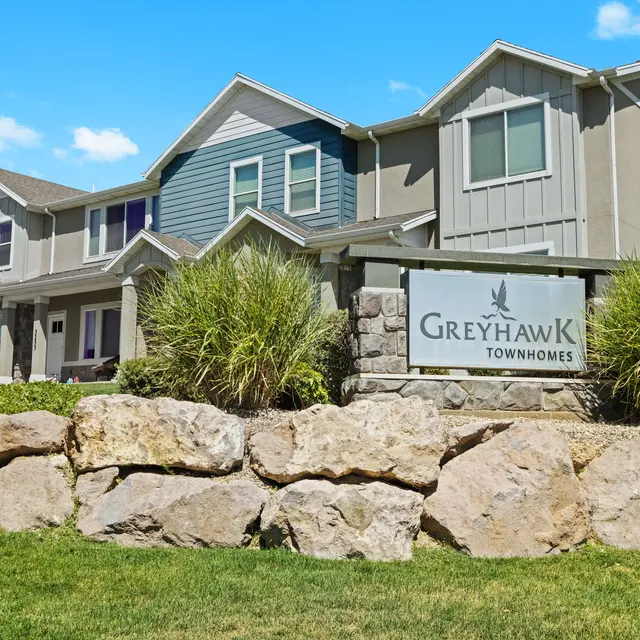 Greyhawk Townhomes Exterior view of Greyhawk Townhomes with a sign and landscaped area in front.