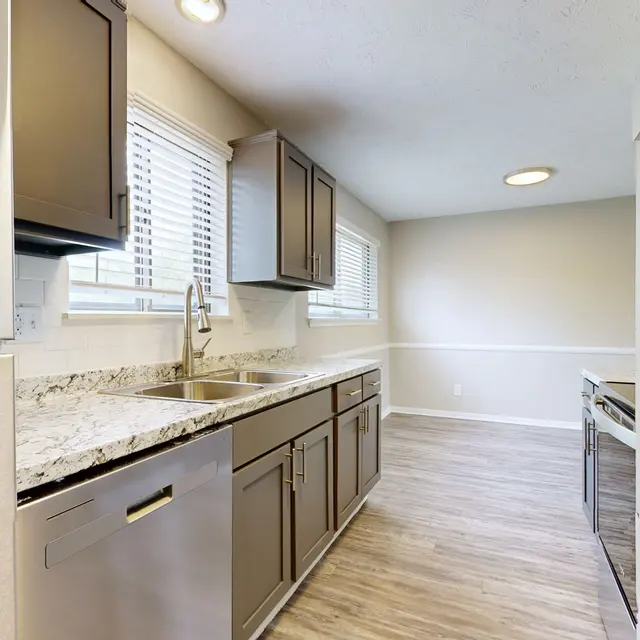 The Hideaway -  A modern kitchen featuring dark cabinets, granite countertops, and stainless steel appliances. Natural light fills the space through the windows.