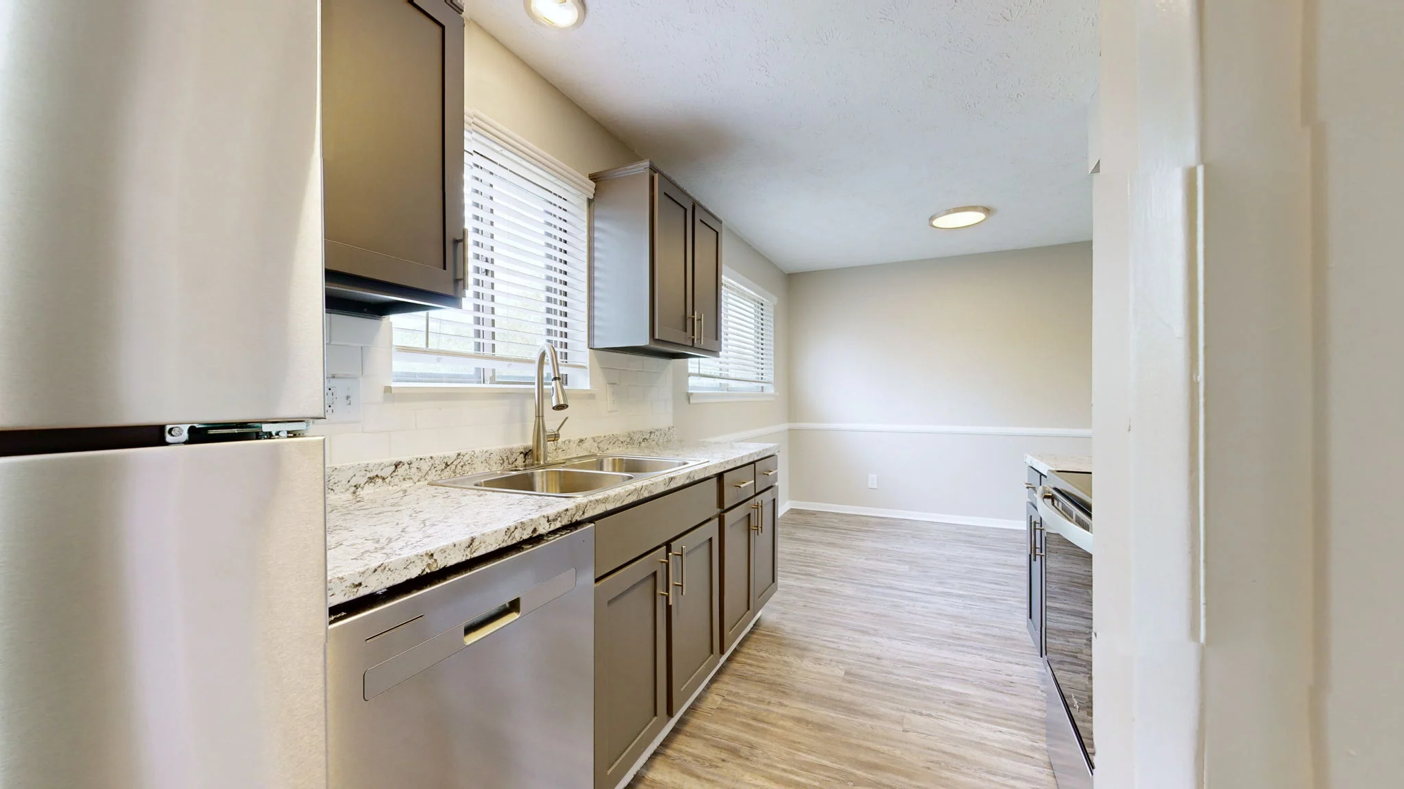 The Hideaway A modern kitchen featuring dark cabinets, granite countertops, and stainless steel appliances. Natural light fills the space through the windows.