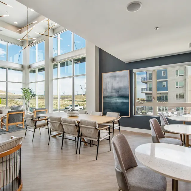 A modern lobby space featuring large windows, comfortable seating, and a mix of tables and chairs.
