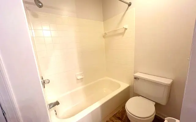 Minimalist Bathroom Interior A clean and simple bathroom featuring a bathtub with a shower, a toilet, and white tiles