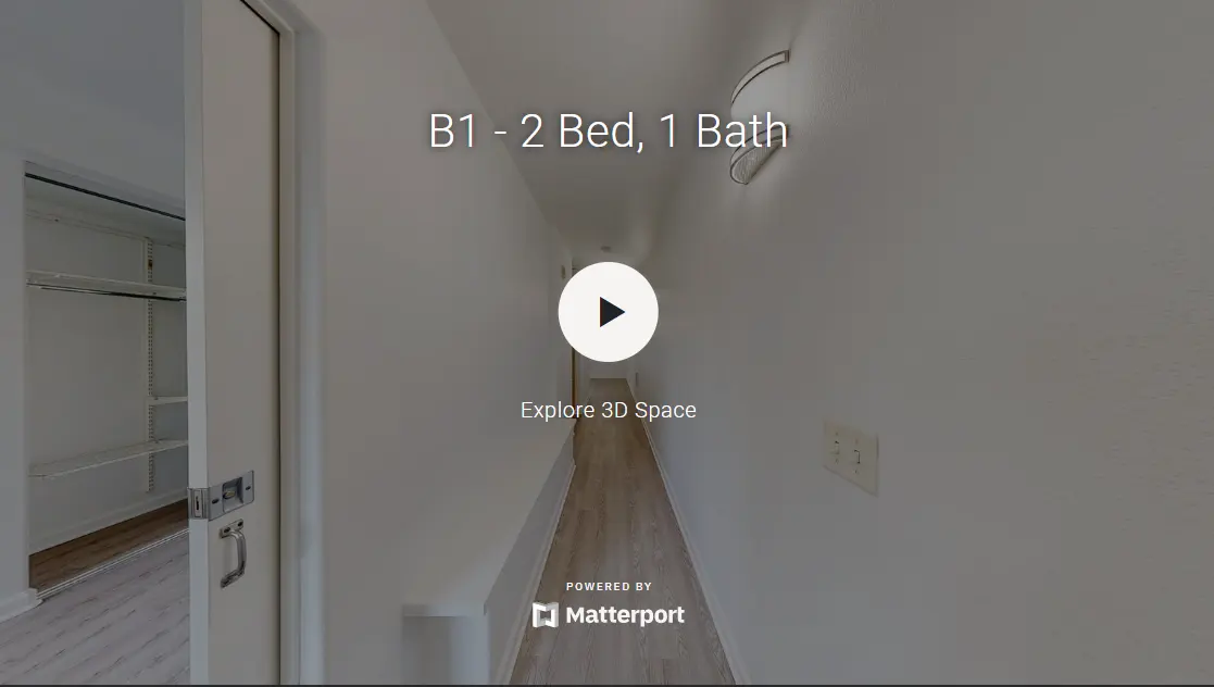 A hallway in an apartment with a view into a room on the left and a play button in the center to explore a 3D space.