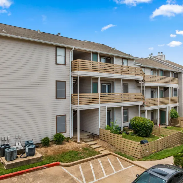 Exterior view of a multi-unit apartment building featuring balconies and landscaped areas.
