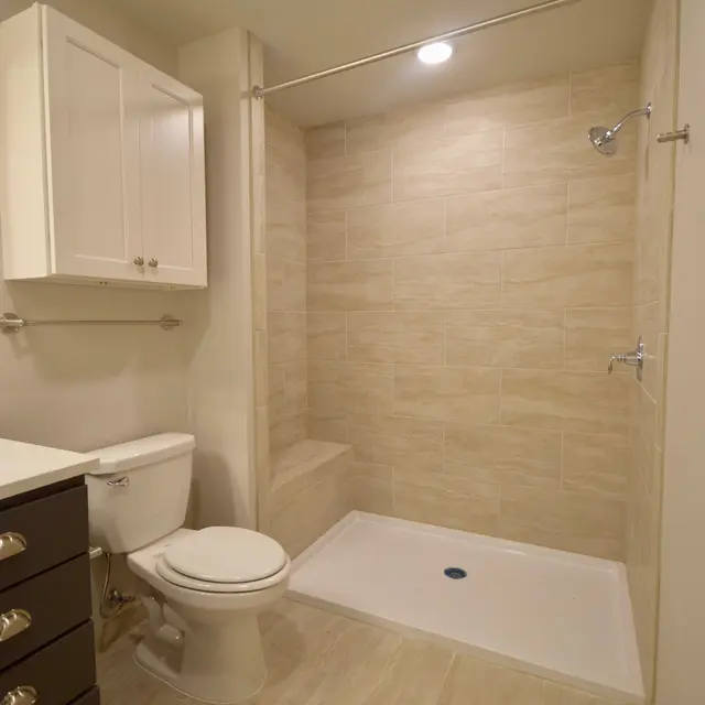 A modern bathroom featuring a shower with a glass door, a toilet, and a sink with cabinets.