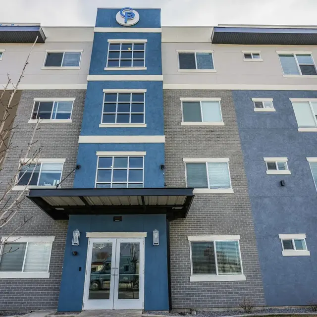Exterior view of a modern apartment building with grey and blue facade