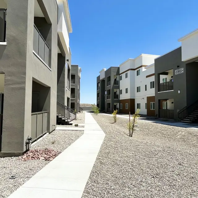 Modern Apartment Complex A pathway lined with two-story apartment buildings on either side, featuring a mixture of colors and balconies.