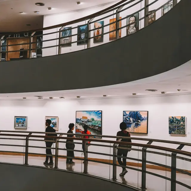 Milwaukee Art Museum Visitors walking through an art gallery with paintings displayed on the walls.