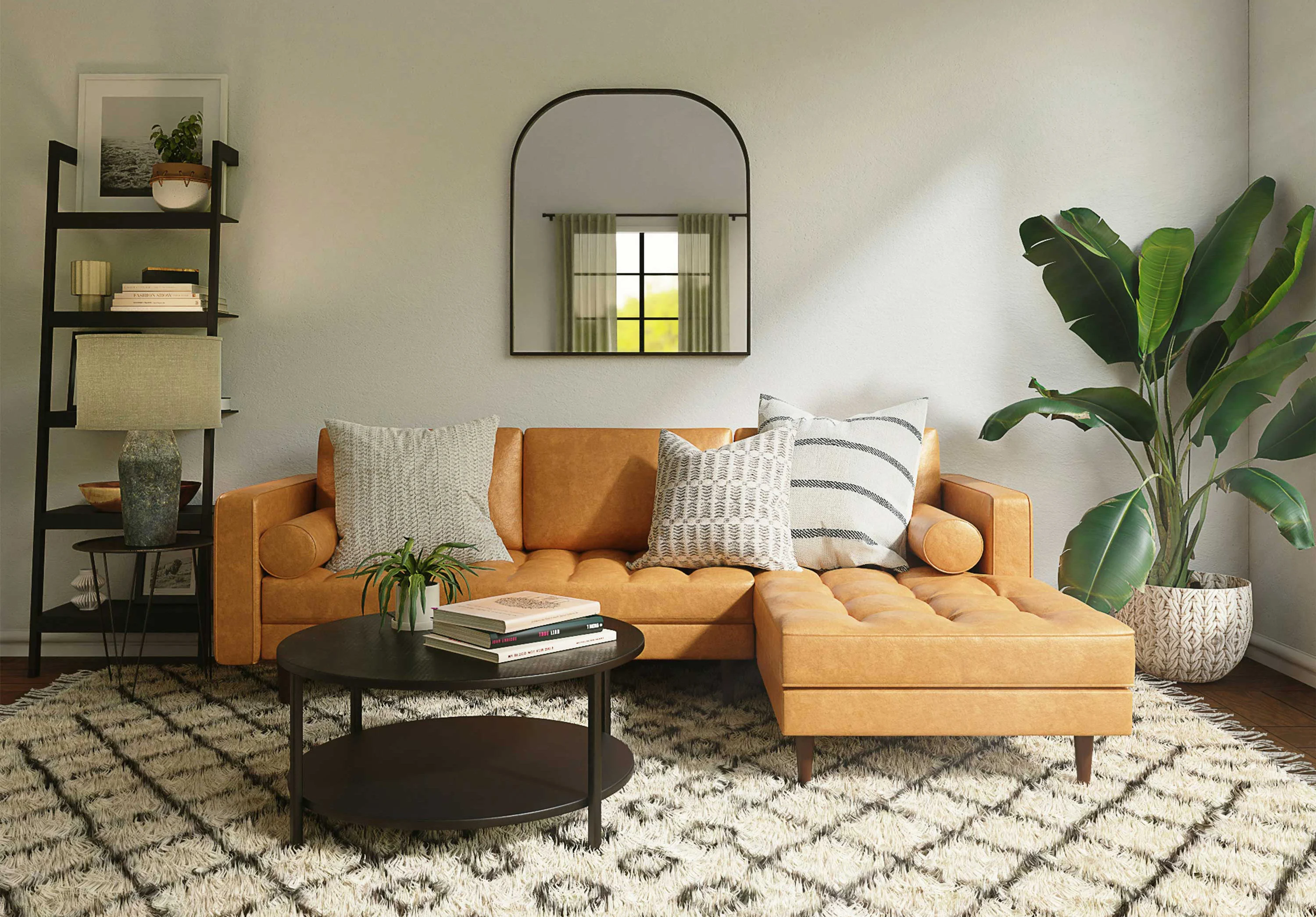 A modern living room featuring a stylish tan sectional sofa with various patterned cushions, a round black coffee table, a textured area rug, and a tall plant. A mirror hangs above the sofa, reflecting natural light from a window.