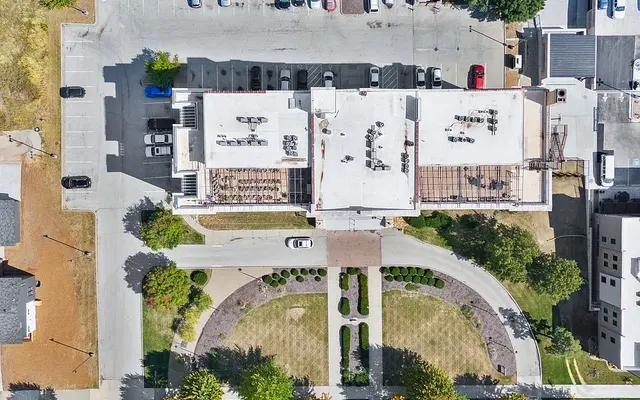 Aerial View of Building with Rooftop Terrace Aerial view of a building with a rooftop patio surrounded by landscaping and parked cars.