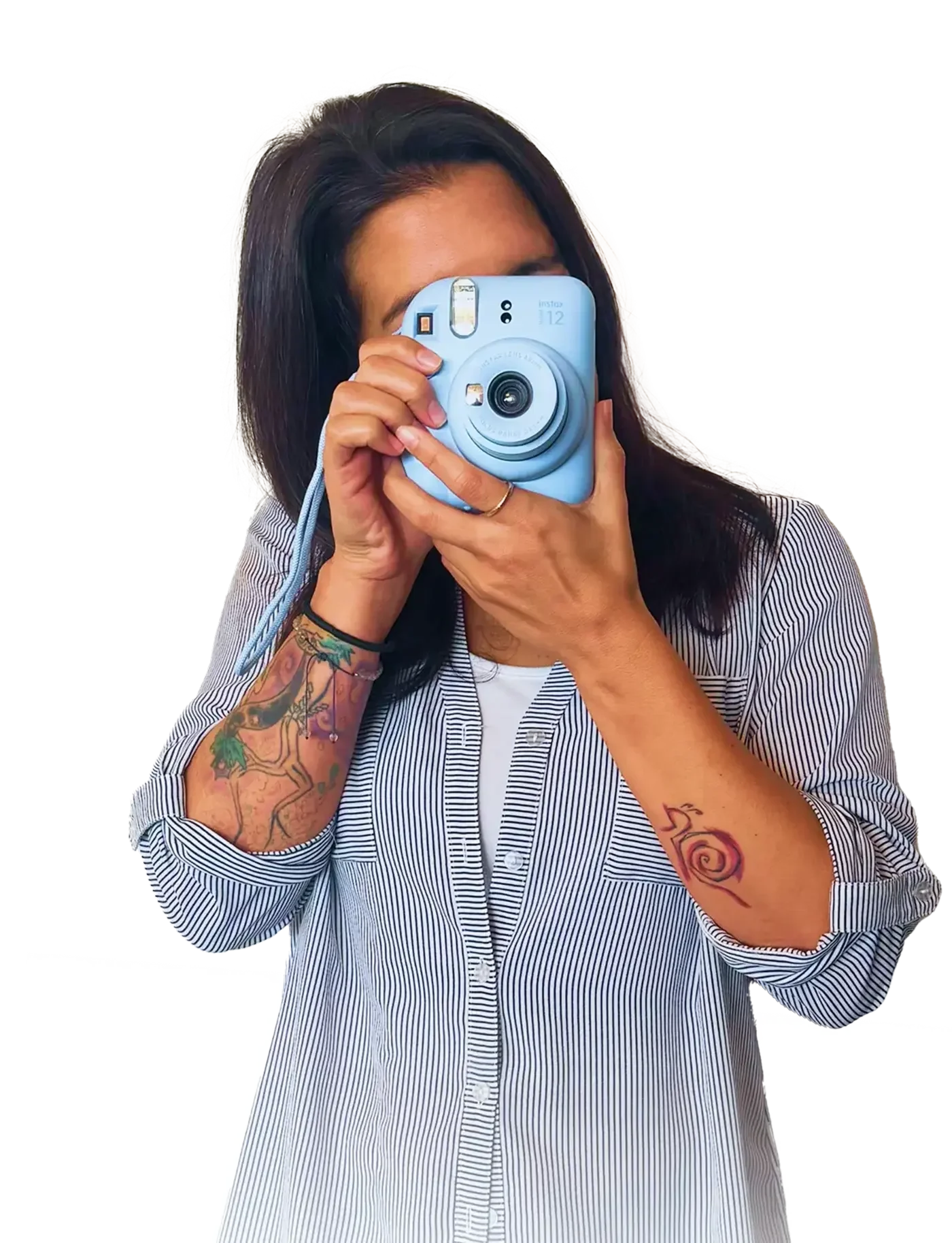 Person Taking a Photo with Instant Camera A person with long hair is holding a light blue instant camera to their face, wearing a striped shirt, and has visible tattoos on their arms.