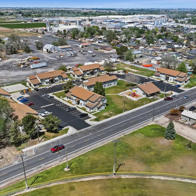 Aerial View of Suburban Neighborhood Aerial view of a suburban neighborhood featuring residential buildings, a road, and surrounding fields.