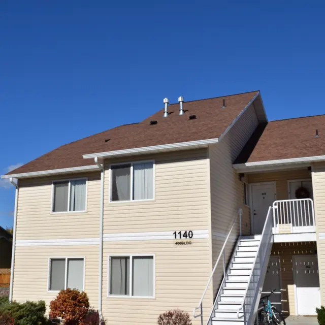 Apartment Building 1140 A two-story apartment building with a light-colored exterior and a staircase leading to a balcony.