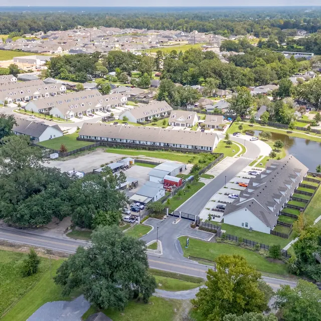 Aerial View of a Residential Neighborhood Aerial view of a residential neighborhood featuring multiple buildings, green spaces, and a winding road.