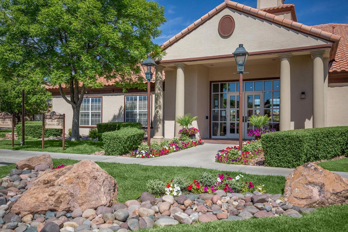 Exterior view of a community building with landscaped flower beds and pathway.