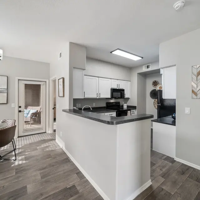 Open-concept apartment interior featuring kitchen, dining area, and wood-style flooring at Bear Canyon Apartments