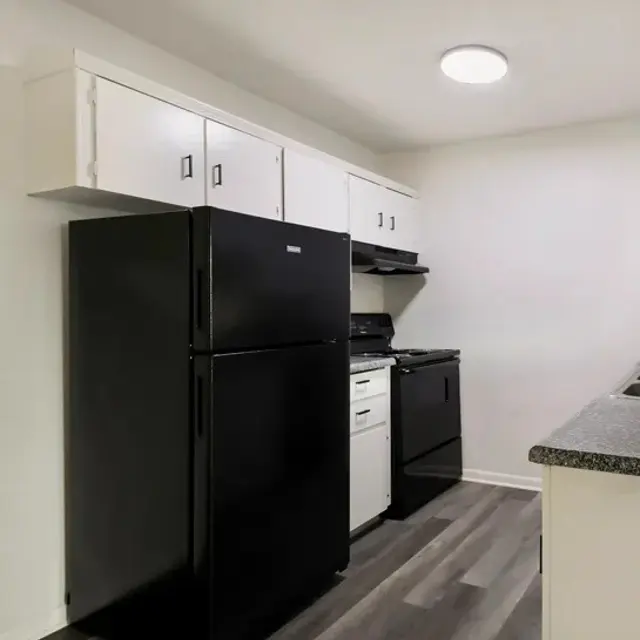 A modern kitchen with black and white appliances, featuring a black refrigerator, a black stove, and white cabinetry.