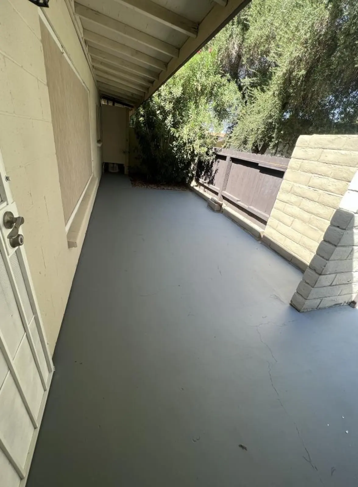 Covered concrete patio beside a block wall and wooden fence.