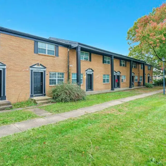 Exterior view of an apartment complex with brick walls and a well-maintained lawn.