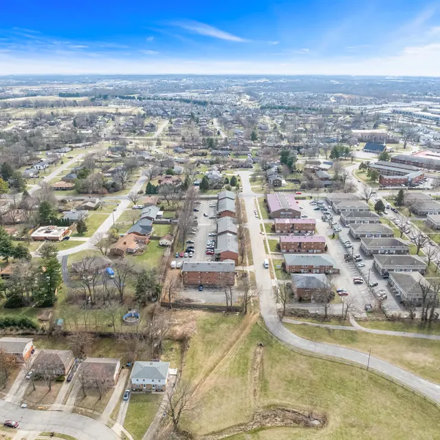 Aerial view of a suburban neighborhood showcasing various residential buildings, roads, and a clear blue sky.