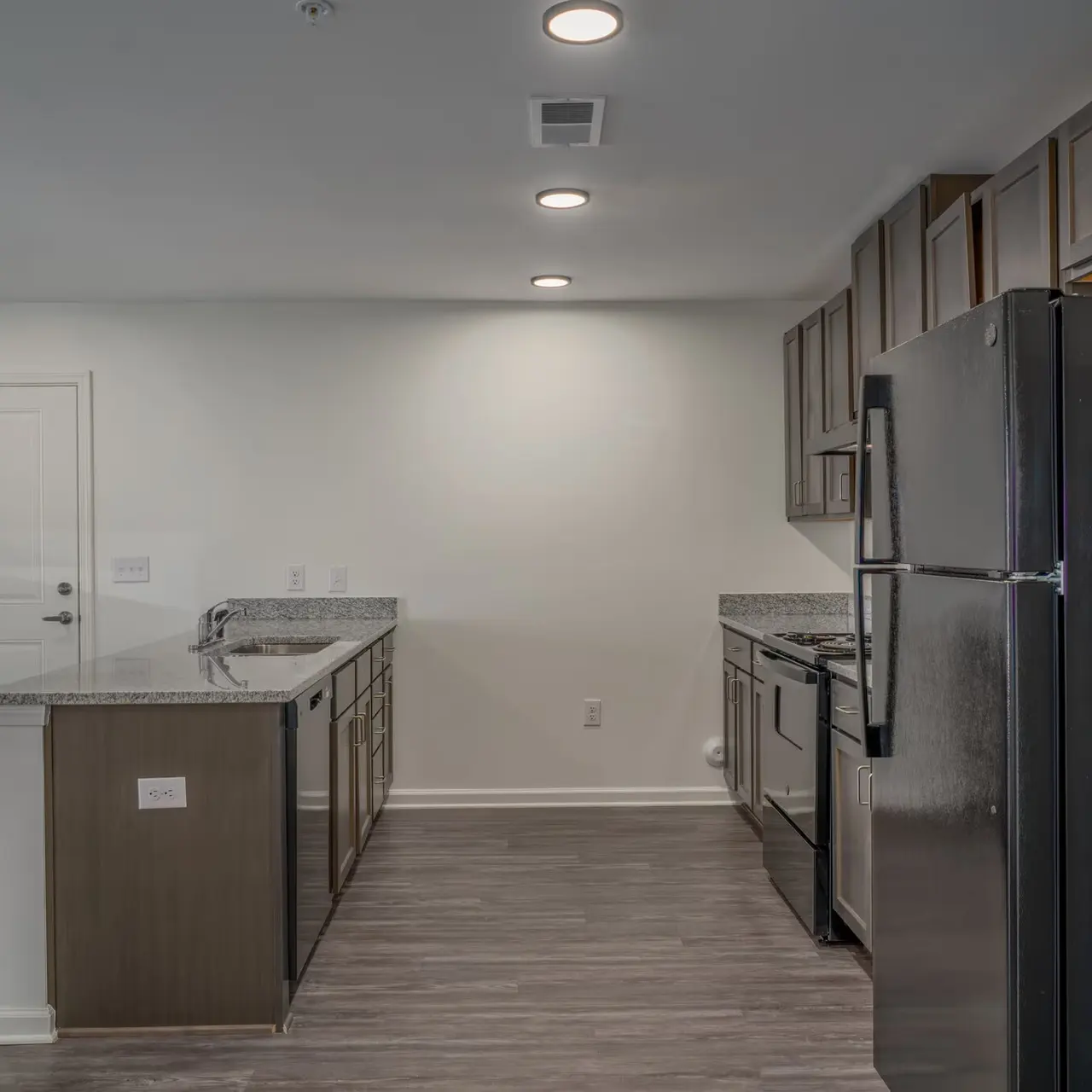 A modern kitchen featuring stainless steel appliances, a granite countertop, and wooden cabinets. The space is bright with recessed lighting and has a neutral color scheme.