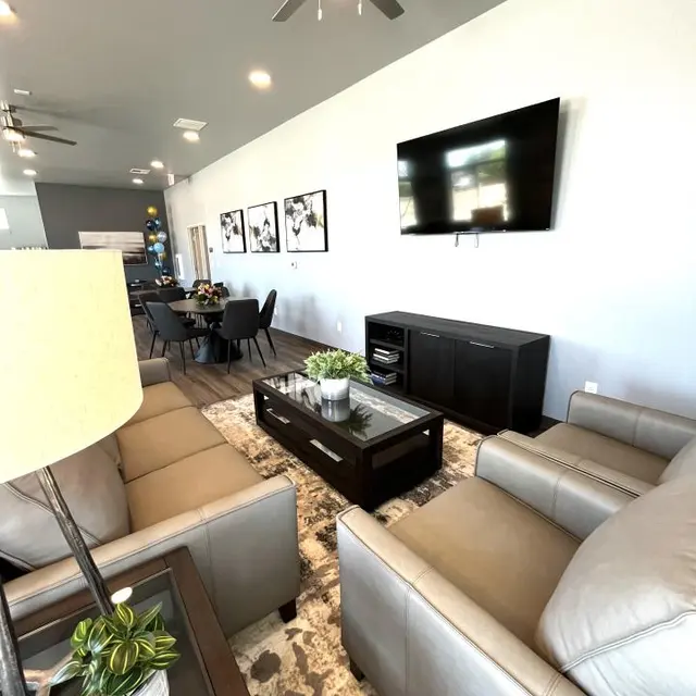 Modern Living Room Interior A modern living room featuring grey sofas, a coffee table with a potted plant, a wall-mounted television, and dining space in the background.