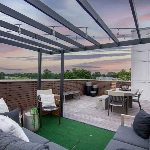 A rooftop terrace featuring stylish furniture, a green rug, and a view of the horizon during twilight.
