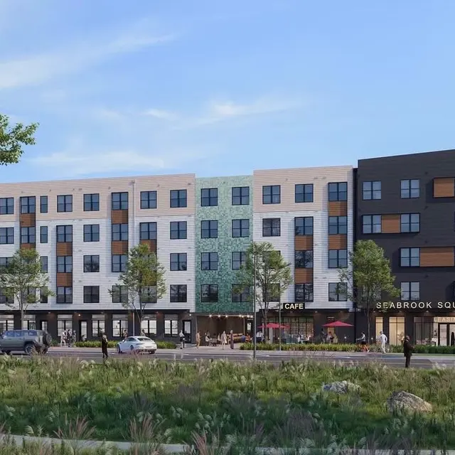 Rendering of a modern apartment building featuring a blend of colors and architectural styles with greenery in the foreground.