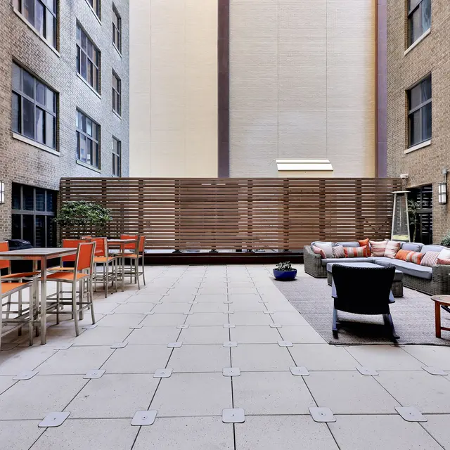 Urban Patio Space A modern urban patio with seating arrangements and plants, surrounded by brick buildings.
