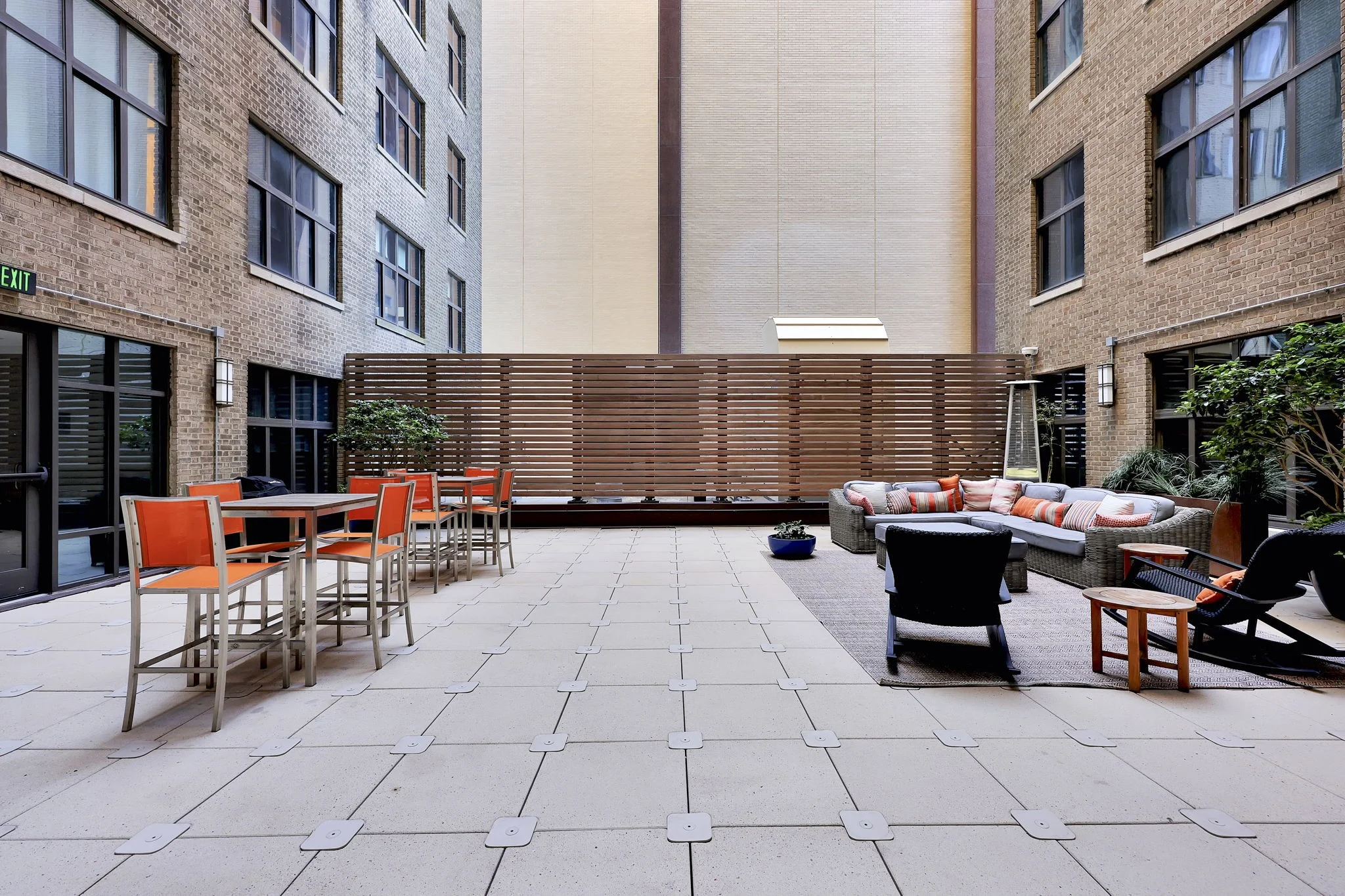 Urban Patio Space A modern urban patio with seating arrangements and plants, surrounded by brick buildings.
