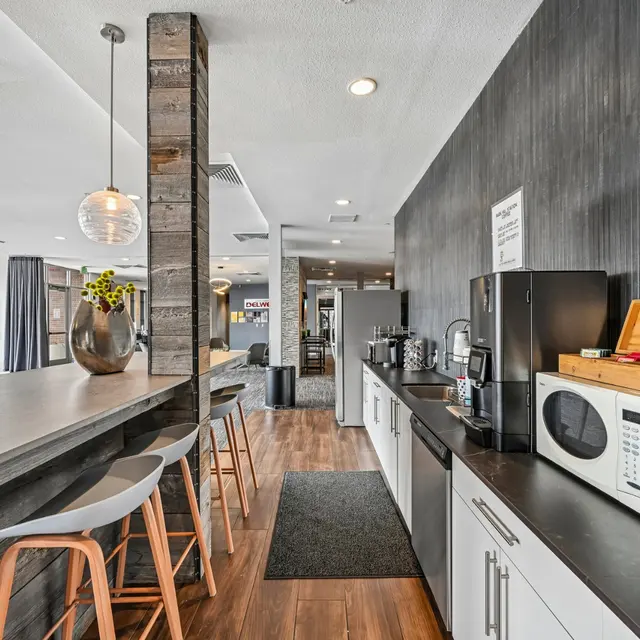 Contemporary Community Kitchen Modern kitchen area with a counter bar and seating, featuring appliances and decorative elements.