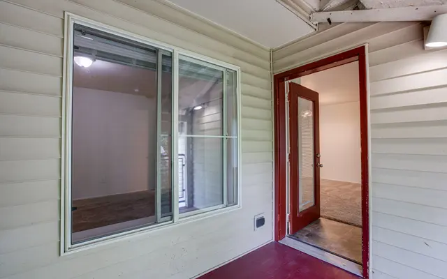 Entryway of a house with a red door and a window looking into the interior.