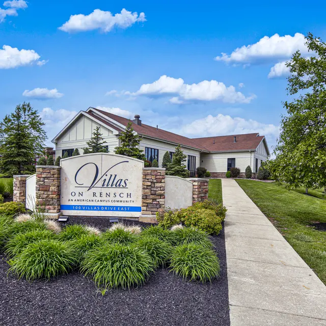 Exterior view of a residential community sign for Villas on Rensch, surrounded by greenery and a pathway.