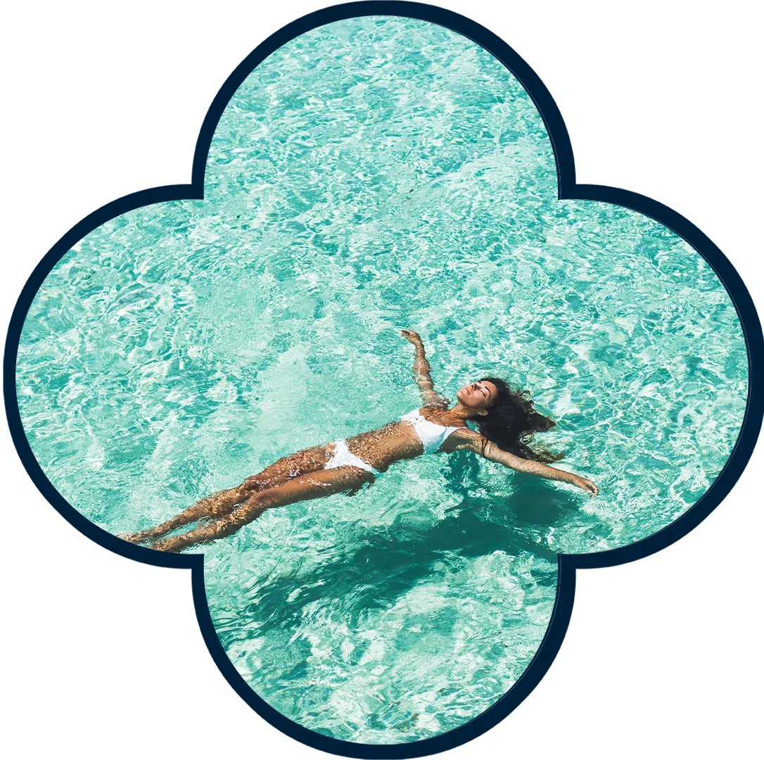Relaxation in the Pool A woman is floating in a turquoise pool, wearing a white bikini. The water reflects light in shimmering patterns around her.