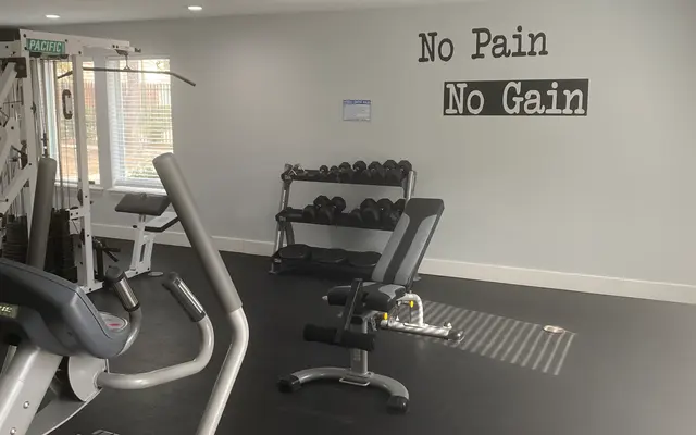 Interior of a modern gym featuring exercise equipment and a motivational wall mural.